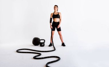 Spor aletlerini kullanarak spor salonunda antrenman yapan genç bir bayan sporcu. Formda kadın vücut çalışıyor. Zindelik, sağlık ve spor hazırlığı kavramları.