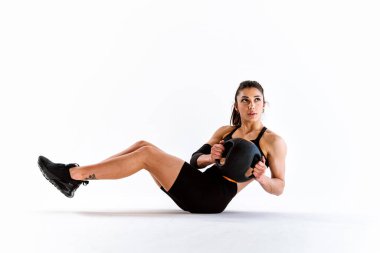 Spor aletlerini kullanarak spor salonunda antrenman yapan genç bir bayan sporcu. Formda kadın vücut çalışıyor. Zindelik, sağlık ve spor hazırlığı kavramları.