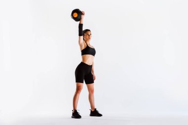 Spor aletlerini kullanarak spor salonunda antrenman yapan genç bir bayan sporcu. Formda kadın vücut çalışıyor. Zindelik, sağlık ve spor hazırlığı kavramları.