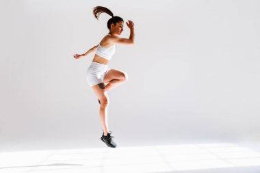 Spor aletlerini kullanarak spor salonunda antrenman yapan genç bir bayan sporcu. Formda kadın vücut çalışıyor. Zindelik, sağlık ve spor hazırlığı kavramları.