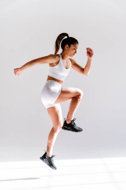 Spor aletlerini kullanarak spor salonunda antrenman yapan genç bir bayan sporcu. Formda kadın vücut çalışıyor. Zindelik, sağlık ve spor hazırlığı kavramları.