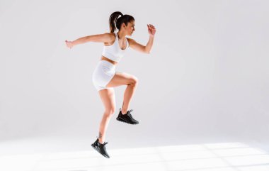 Spor aletlerini kullanarak spor salonunda antrenman yapan genç bir bayan sporcu. Formda kadın vücut çalışıyor. Zindelik, sağlık ve spor hazırlığı kavramları.