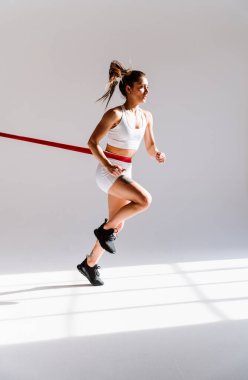 Spor aletlerini kullanarak spor salonunda antrenman yapan genç bir bayan sporcu. Formda kadın vücut çalışıyor. Zindelik, sağlık ve spor hazırlığı kavramları.
