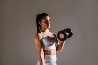 Spor aletlerini kullanarak spor salonunda antrenman yapan genç bir bayan sporcu. Formda kadın vücut çalışıyor. Zindelik, sağlık ve spor hazırlığı kavramları.