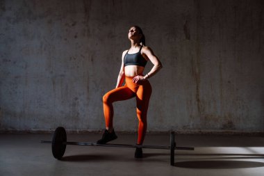Spor aletlerini kullanarak spor salonunda antrenman yapan genç bir bayan sporcu. Formda kadın vücut çalışıyor. Zindelik, sağlık ve spor hazırlığı kavramları.