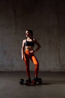 Spor aletlerini kullanarak spor salonunda antrenman yapan genç bir bayan sporcu. Formda kadın vücut çalışıyor. Zindelik, sağlık ve spor hazırlığı kavramları.