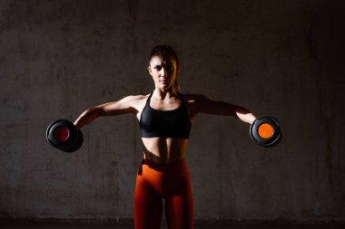 Spor aletlerini kullanarak spor salonunda antrenman yapan genç bir bayan sporcu. Formda kadın vücut çalışıyor. Zindelik, sağlık ve spor hazırlığı kavramları.