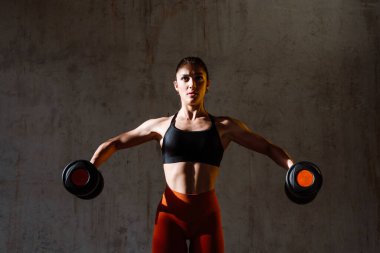 Spor aletlerini kullanarak spor salonunda antrenman yapan genç bir bayan sporcu. Formda kadın vücut çalışıyor. Zindelik, sağlık ve spor hazırlığı kavramları.