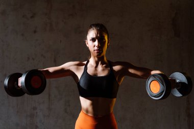 Spor aletlerini kullanarak spor salonunda antrenman yapan genç bir bayan sporcu. Formda kadın vücut çalışıyor. Zindelik, sağlık ve spor hazırlığı kavramları.