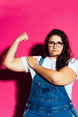 Ayrıca stüdyoda poz veren ve renkli arka planlarda eğlenen cüsseli bir kadın. Direkt stüdyo ışık çekimleri