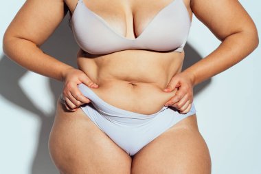 Ayrıca stüdyo içinde iç çamaşırlarıyla poz veren cüsseli bir kadın. Beyaz arka planda bir model. Hard Light stüdyo çekimi