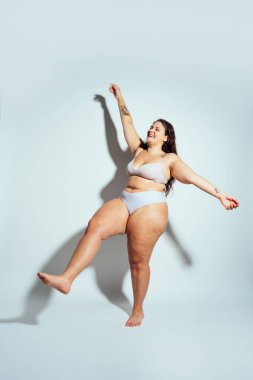 Ayrıca stüdyo içinde iç çamaşırlarıyla poz veren cüsseli bir kadın. Beyaz arka planda bir model. Hard Light stüdyo çekimi