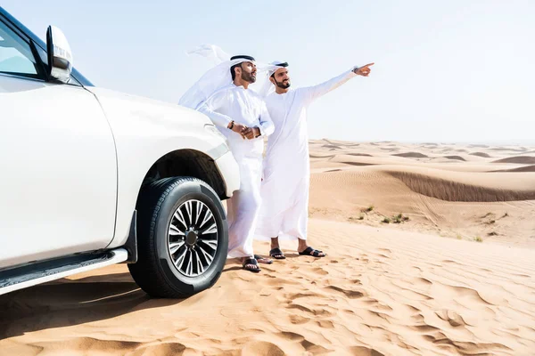 砂漠で4 4台の車を運転する伝統的なエミレーツ アラブ カンドゥラを身に着けている中東の2人の男性 ドバイの砂丘でアラビア人のイスラム教徒の友人が遠足 — ストック写真