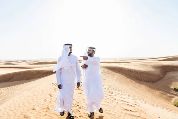砂漠で伝統的なエミレーツ アラブ カンドゥラの絆を身に着けている中東の2人の男性 ドバイの砂丘で会うアラビア人のイスラム教徒の友人 — ストック写真