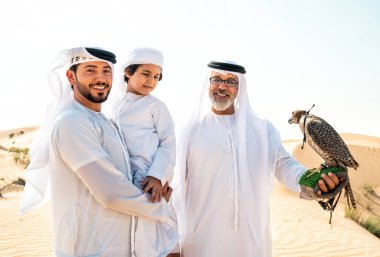 Dubai çölünde safari yapan üç nesillik bir aile. Büyükbaba, oğul ve torun doğada birlikte vakit geçirip şahin kuşlarını eğitiyorlar..