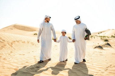 Dubai çölünde safari yapan üç nesillik bir aile. Büyükbaba, oğul ve torun doğada birlikte vakit geçirip şahin kuşlarını eğitiyorlar..