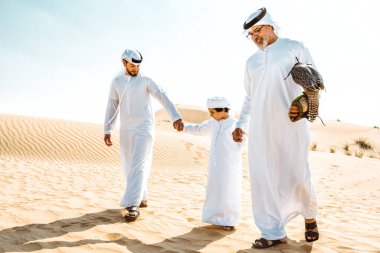 Dubai çölünde safari yapan üç nesillik bir aile. Büyükbaba, oğul ve torun doğada birlikte vakit geçirip şahin kuşlarını eğitiyorlar..