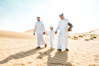 Dubai çölünde safari yapan üç nesillik bir aile. Büyükbaba, oğul ve torun doğada birlikte vakit geçirip şahin kuşlarını eğitiyorlar..