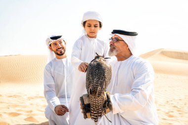 Dubai çölünde safari yapan üç nesillik bir aile. Büyükbaba, oğul ve torun doğada birlikte vakit geçirip şahin kuşlarını eğitiyorlar..