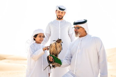 Dubai çölünde safari yapan üç nesillik bir aile. Büyükbaba, oğul ve torun doğada birlikte vakit geçirip şahin kuşlarını eğitiyorlar..