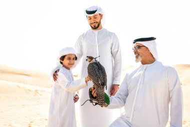 Dubai çölünde safari yapan üç nesillik bir aile. Büyükbaba, oğul ve torun doğada birlikte vakit geçirip şahin kuşlarını eğitiyorlar..
