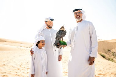 Dubai çölünde safari yapan üç nesillik bir aile. Büyükbaba, oğul ve torun doğada birlikte vakit geçirip şahin kuşlarını eğitiyorlar..