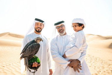 Dubai çölünde safari yapan üç nesillik bir aile. Büyükbaba, oğul ve torun doğada birlikte vakit geçirip şahin kuşlarını eğitiyorlar..