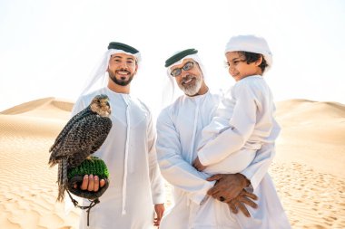 Dubai çölünde safari yapan üç nesillik bir aile. Büyükbaba, oğul ve torun doğada birlikte vakit geçirip şahin kuşlarını eğitiyorlar..