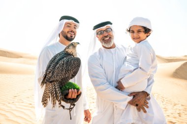 Dubai çölünde safari yapan üç nesillik bir aile. Büyükbaba, oğul ve torun doğada birlikte vakit geçirip şahin kuşlarını eğitiyorlar..