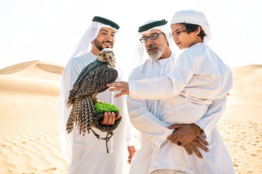 Dubai çölünde safari yapan üç nesillik bir aile. Büyükbaba, oğul ve torun doğada birlikte vakit geçirip şahin kuşlarını eğitiyorlar..