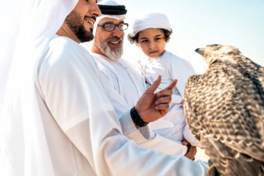 Dubai çölünde safari yapan üç nesillik bir aile. Büyükbaba, oğul ve torun doğada birlikte vakit geçirip şahin kuşlarını eğitiyorlar..