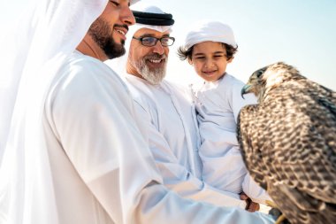 Dubai çölünde safari yapan üç nesillik bir aile. Büyükbaba, oğul ve torun doğada birlikte vakit geçirip şahin kuşlarını eğitiyorlar..