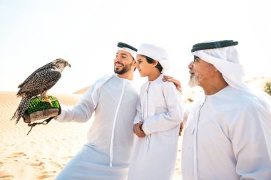 Dubai çölünde safari yapan üç nesillik bir aile. Büyükbaba, oğul ve torun doğada birlikte vakit geçirip şahin kuşlarını eğitiyorlar..