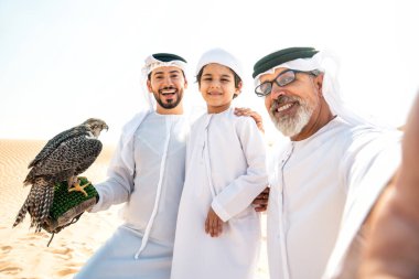 Dubai çölünde safari yapan üç nesillik bir aile. Büyükbaba, oğul ve torun doğada birlikte vakit geçirip şahin kuşlarını eğitiyorlar..