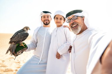 Dubai çölünde safari yapan üç nesillik bir aile. Büyükbaba, oğul ve torun doğada birlikte vakit geçirip şahin kuşlarını eğitiyorlar..