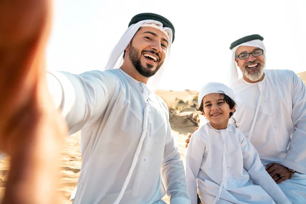 三代家庭穿着白色的坎杜拉服装在迪拜沙漠中进行了一次旅行 儿子和孙子在大自然中呆在一起 — 图库照片