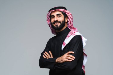 Stüdyoda geleneksel Suudi kıyafetleri olan yakışıklı Arap orta doğulu adam - Arap Müslüman yetişkin iş adamı beyaz arka planda izole edilmiş thwab portresi takıyor.