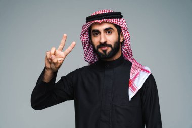 Stüdyoda geleneksel Suudi kıyafetleri olan yakışıklı Arap orta doğulu adam - Arap Müslüman yetişkin iş adamı beyaz arka planda izole edilmiş thwab portresi takıyor.