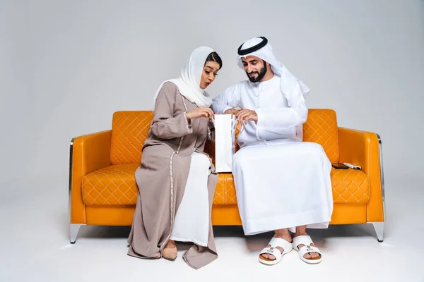 美しいアラブ中東の幸せな恋人のカップルは 伝統的なアバヤを身に着け アラブ系イスラム教徒のアダルト大人のソファーに座って ドバイで結合し 楽しんでいます アラブ首長国連邦 — ストック写真
