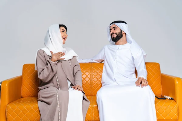 美しいアラブ中東の幸せな恋人のカップルは 伝統的なアバヤを身に着け アラブ系イスラム教徒のアダルト大人のソファーに座って ドバイで結合し 楽しんでいます アラブ首長国連邦 — ストック写真