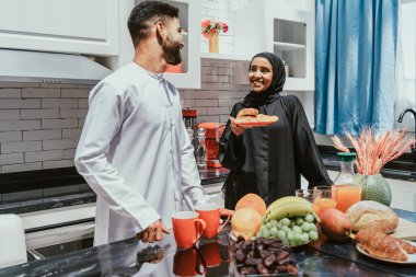 Geleneksel Arap kıyafetleri içinde mutlu bir orta doğu çifti - evli Arap karı-koca evde birbirine bağlanıyor, ilişki kavramları, ev hayatı ve emirati yaşam tarzı