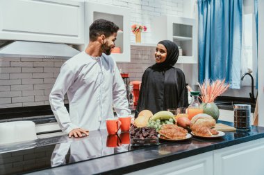Geleneksel Arap kıyafetleri içinde mutlu bir orta doğu çifti - evli Arap karı-koca evde birbirine bağlanıyor, ilişki kavramları, ev hayatı ve emirati yaşam tarzı
