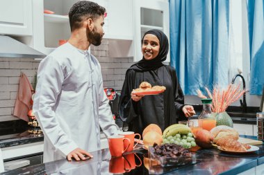 Geleneksel Arap kıyafetleri içinde mutlu bir orta doğu çifti - evli Arap karı-koca evde birbirine bağlanıyor, ilişki kavramları, ev hayatı ve emirati yaşam tarzı