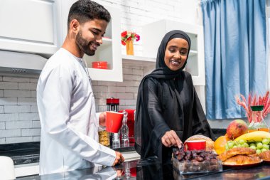 Geleneksel Arap kıyafetleri içinde mutlu bir orta doğu çifti - evli Arap karı-koca evde birbirine bağlanıyor, ilişki kavramları, ev hayatı ve emirati yaşam tarzı
