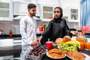 Geleneksel Arap kıyafetleri içinde mutlu bir orta doğu çifti - evli Arap karı-koca evde birbirine bağlanıyor, ilişki kavramları, ev hayatı ve emirati yaşam tarzı