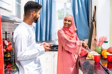 Geleneksel Arap kıyafetleri içinde mutlu bir orta doğu çifti - evli Arap karı-koca evde birbirine bağlanıyor, ilişki kavramları, ev hayatı ve emirati yaşam tarzı