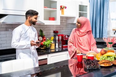 Geleneksel Arap kıyafetleri içinde mutlu bir orta doğu çifti - evli Arap karı-koca evde birbirine bağlanıyor, ilişki kavramları, ev hayatı ve emirati yaşam tarzı