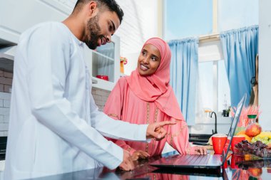 Geleneksel Arap kıyafetleri içinde mutlu bir orta doğu çifti - evli Arap karı-koca evde birbirine bağlanıyor, ilişki kavramları, ev hayatı ve emirati yaşam tarzı