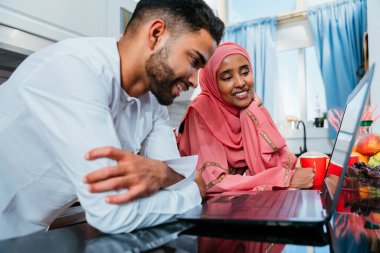 Geleneksel Arap kıyafetleri içinde mutlu bir orta doğu çifti - evli Arap karı-koca evde birbirine bağlanıyor, ilişki kavramları, ev hayatı ve emirati yaşam tarzı