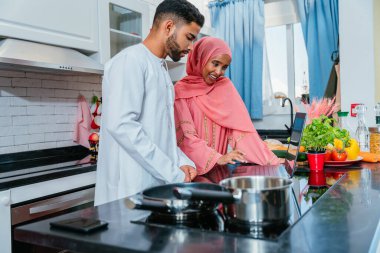 Geleneksel Arap kıyafetleri içinde mutlu bir orta doğu çifti - evli Arap karı-koca evde birbirine bağlanıyor, ilişki kavramları, ev hayatı ve emirati yaşam tarzı